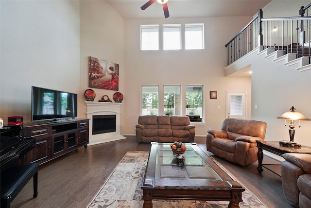 living room featuring a towering ceiling, dark hardwood / wood-style flooring, and plenty of natural light