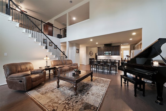 living room with dark hardwood / wood-style flooring and a towering ceiling