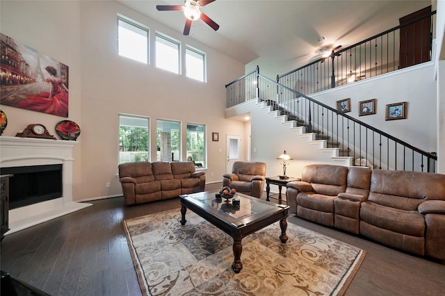 living room featuring ceiling fan, dark wood-type flooring, and a high ceiling