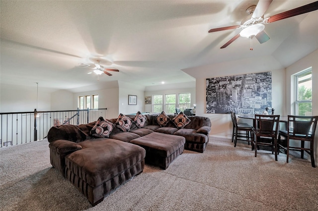 living room with ceiling fan, plenty of natural light, carpet floors, and a textured ceiling