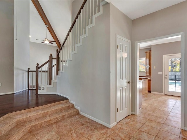 staircase with ceiling fan, beamed ceiling, and high vaulted ceiling