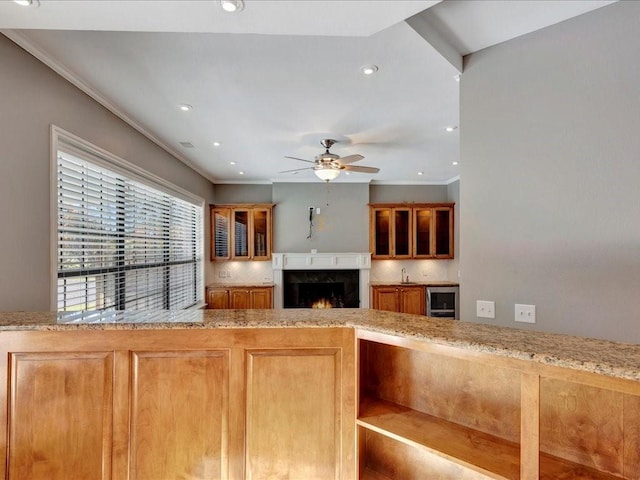 kitchen featuring ceiling fan, a fireplace, beverage cooler, and ornamental molding