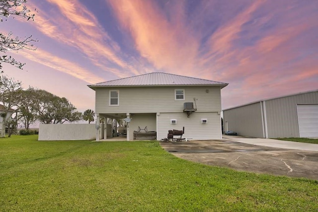 rear view of house with a carport, metal roof, a lawn, and a patio