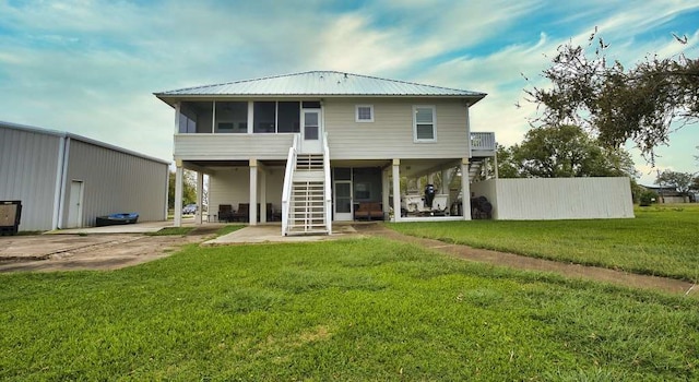 rear view of house featuring a patio, a lawn, a sunroom, metal roof, and stairs