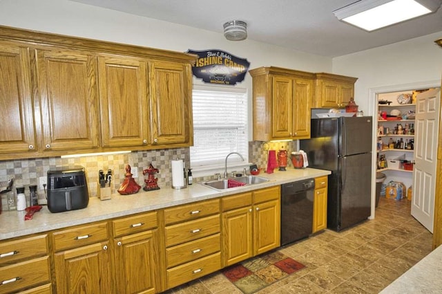 kitchen featuring light countertops, backsplash, brown cabinetry, a sink, and black appliances