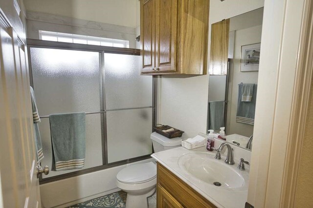 full bathroom featuring tile patterned floors, vanity, toilet, and shower / bath combination with glass door