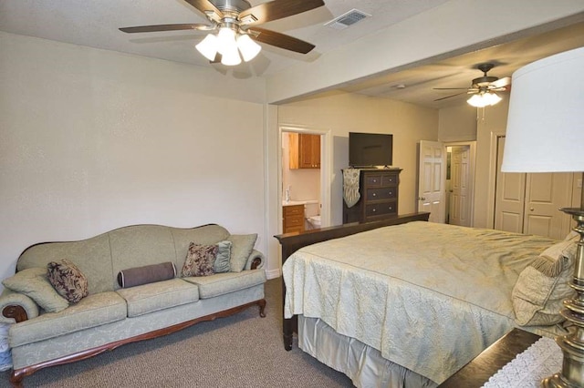 carpeted bedroom with ceiling fan, visible vents, and ensuite bathroom