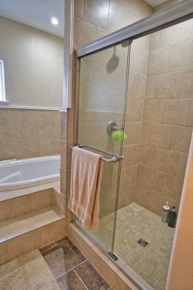 full bath with stone finish flooring, a shower stall, and a bath