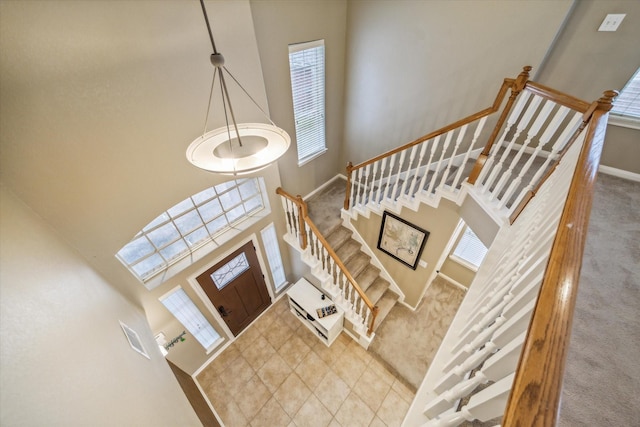 foyer entrance featuring carpet flooring and a high ceiling