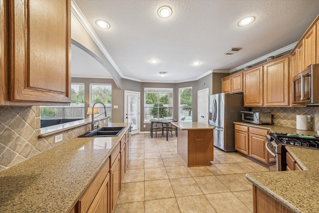 kitchen featuring sink, a center island, stainless steel appliances, light stone counters, and ornamental molding