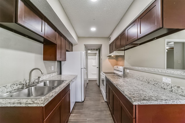 kitchen with dark brown cabinets, a textured ceiling, white appliances, sink, and hardwood / wood-style flooring