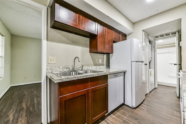 kitchen featuring a textured ceiling, light wood-type flooring, white appliances, and sink