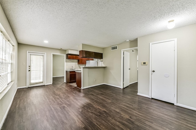 kitchen featuring kitchen peninsula, dark wood-type flooring, a textured ceiling, and white refrigerator