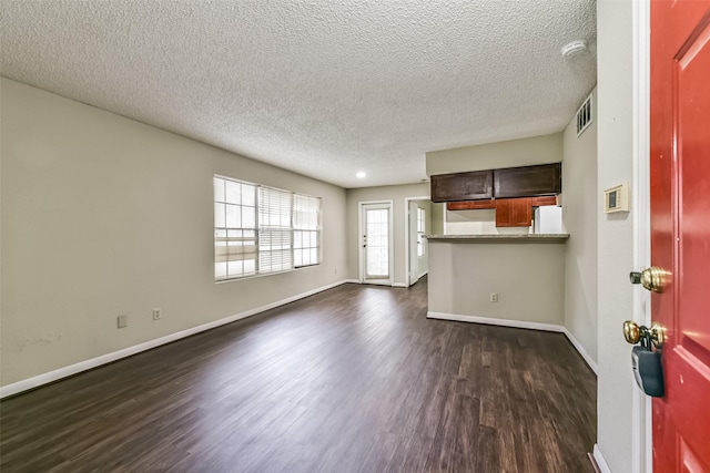 unfurnished living room featuring dark wood-type flooring and a textured ceiling