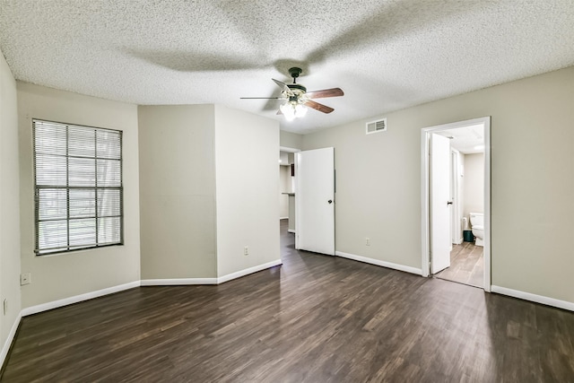 unfurnished bedroom featuring a textured ceiling, ceiling fan, dark wood-type flooring, and ensuite bath