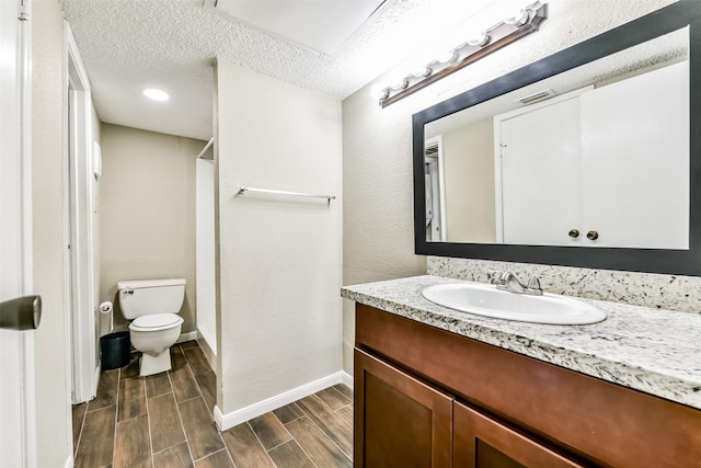 bathroom with a textured ceiling, vanity, hardwood / wood-style flooring, and toilet