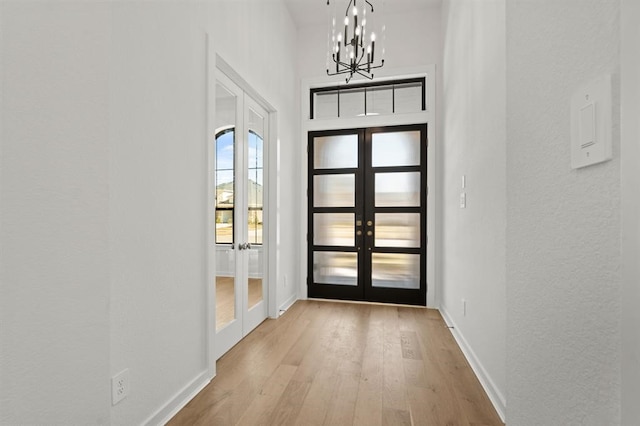 doorway to outside with french doors, a notable chandelier, and light wood-type flooring