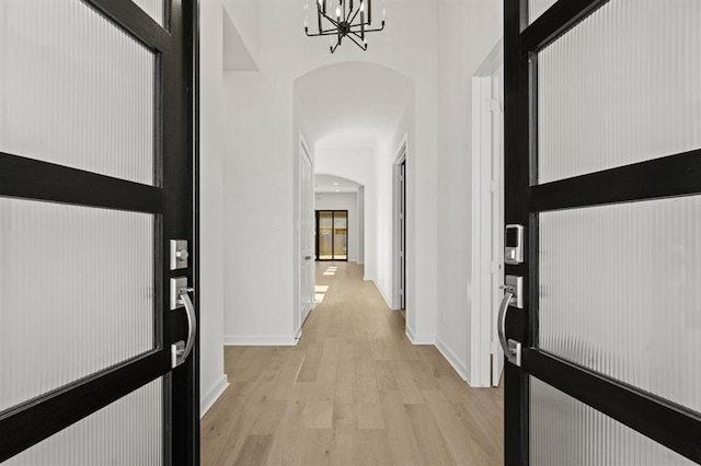 hallway with an inviting chandelier and light hardwood / wood-style floors