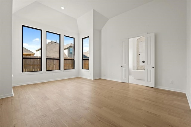 spare room featuring vaulted ceiling, light hardwood / wood-style flooring, and a wealth of natural light