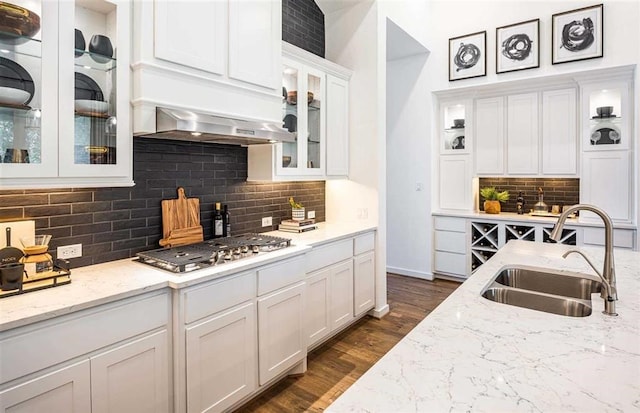 kitchen featuring white cabinetry, stainless steel gas cooktop, light stone countertops, range hood, and sink