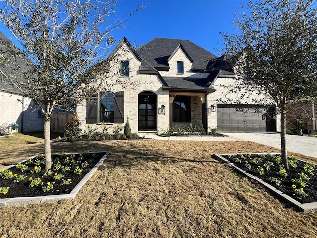 french country inspired facade featuring a garage and a front lawn