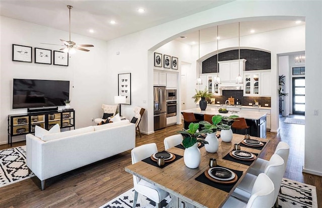 dining room with ceiling fan with notable chandelier and dark wood-type flooring