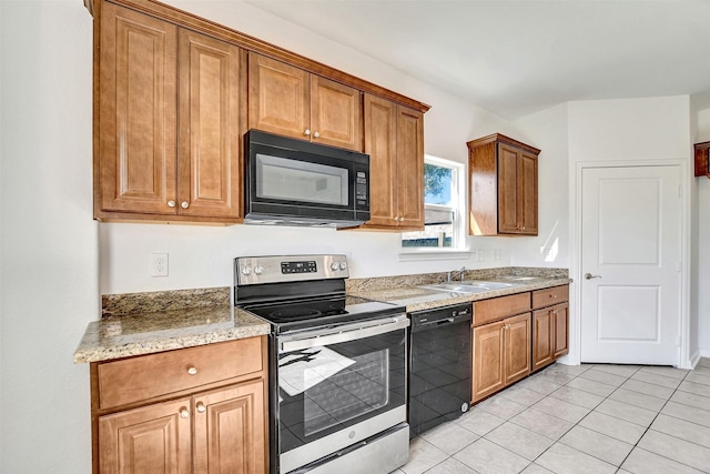 kitchen with light tile patterned floors, sink, light stone counters, and black appliances