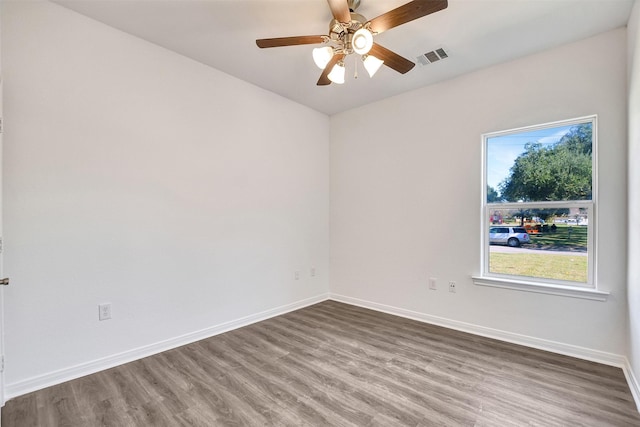 empty room with a wealth of natural light, hardwood / wood-style floors, and ceiling fan