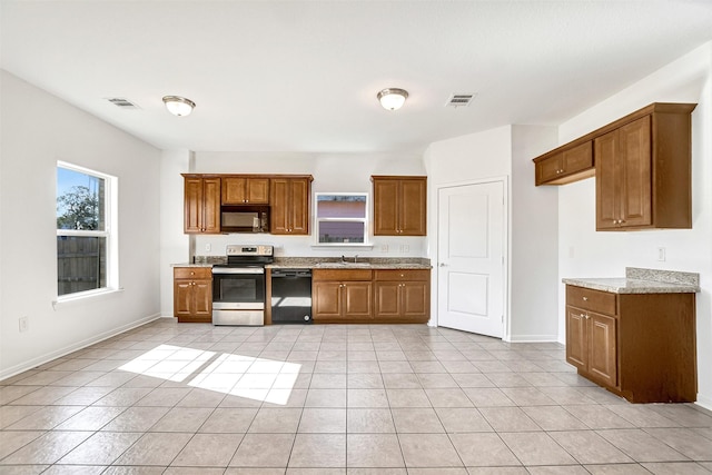 kitchen with light stone countertops, sink, light tile patterned floors, and black appliances