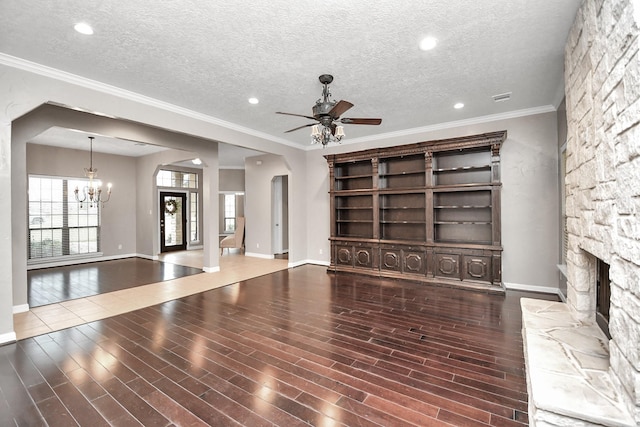 unfurnished living room featuring a fireplace, dark hardwood / wood-style flooring, ceiling fan with notable chandelier, and a textured ceiling