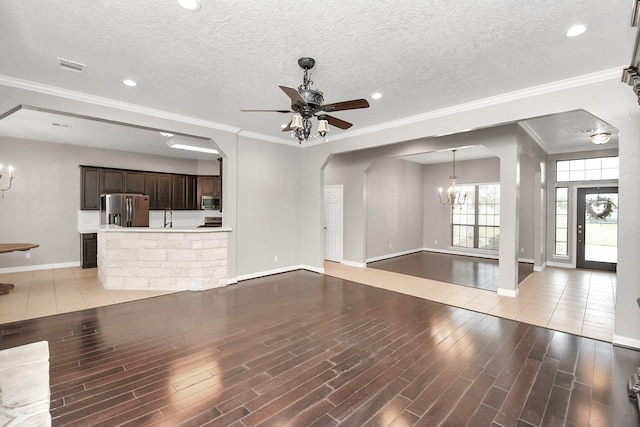 unfurnished living room with ceiling fan with notable chandelier, a textured ceiling, and light hardwood / wood-style flooring