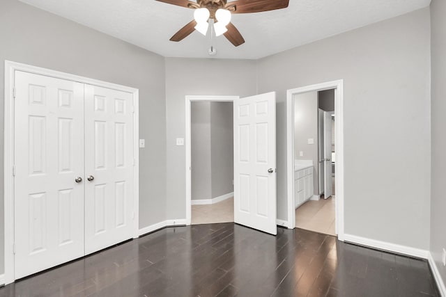 unfurnished bedroom featuring ceiling fan, a closet, dark wood-type flooring, and a textured ceiling