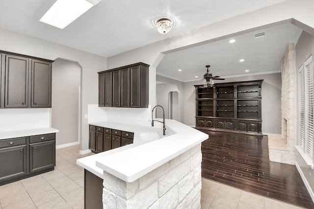 kitchen featuring dark brown cabinets, a textured ceiling, ceiling fan, sink, and light hardwood / wood-style floors