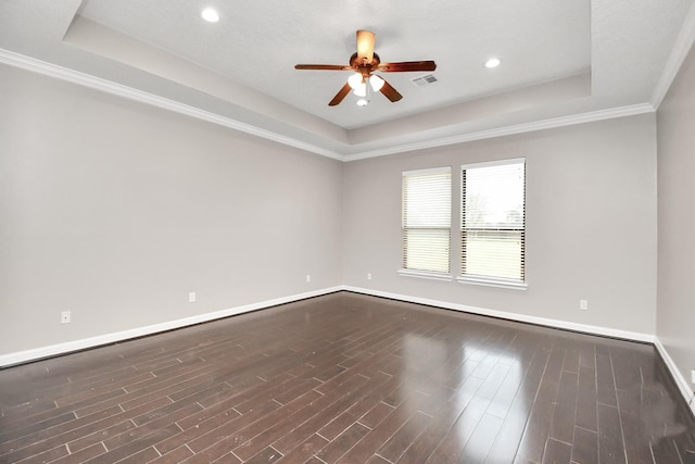 spare room featuring a raised ceiling, ceiling fan, crown molding, and dark wood-type flooring