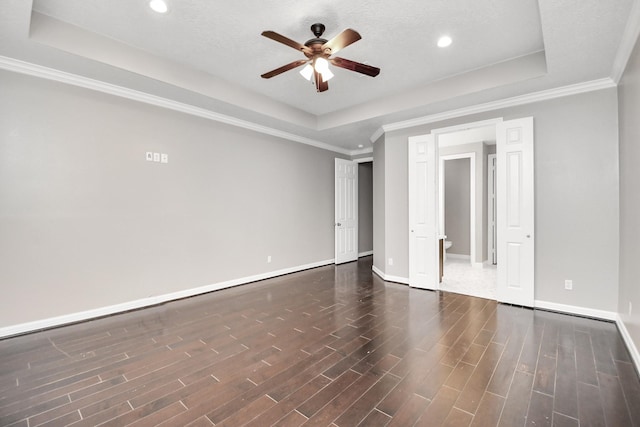 unfurnished bedroom with ceiling fan, dark hardwood / wood-style flooring, crown molding, and a tray ceiling