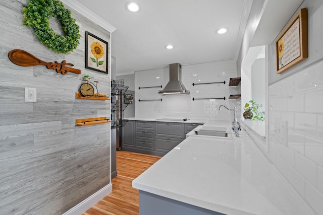 kitchen featuring gray cabinetry, wall chimney range hood, sink, black electric cooktop, and light hardwood / wood-style floors