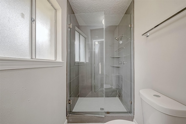 bathroom with toilet, a shower with door, and a textured ceiling