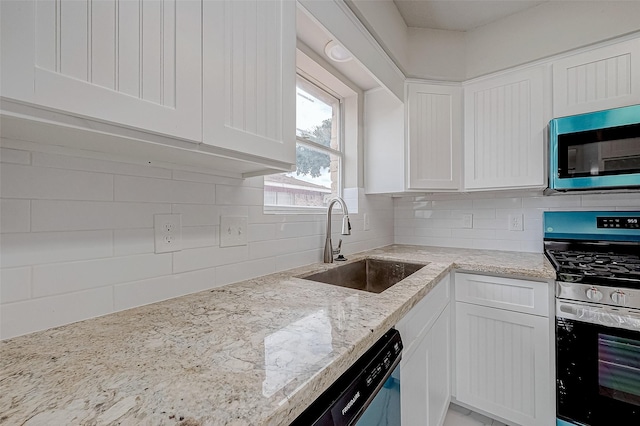 kitchen with decorative backsplash, light stone counters, stainless steel appliances, sink, and white cabinetry