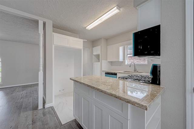 kitchen with white cabinetry, light stone countertops, a textured ceiling, and light wood-type flooring