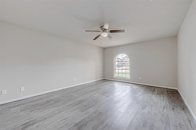 empty room featuring a textured ceiling, light wood-type flooring, and ceiling fan