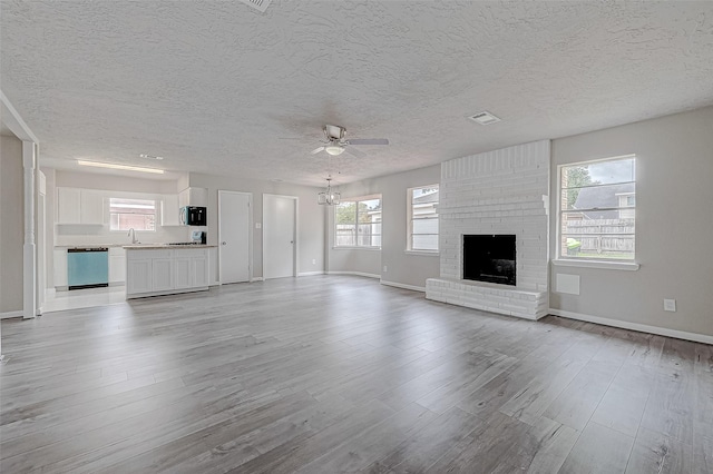 unfurnished living room with a fireplace, a textured ceiling, light hardwood / wood-style flooring, and ceiling fan