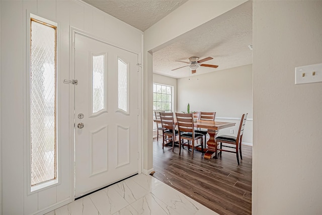 foyer with ceiling fan, hardwood / wood-style floors, and a textured ceiling