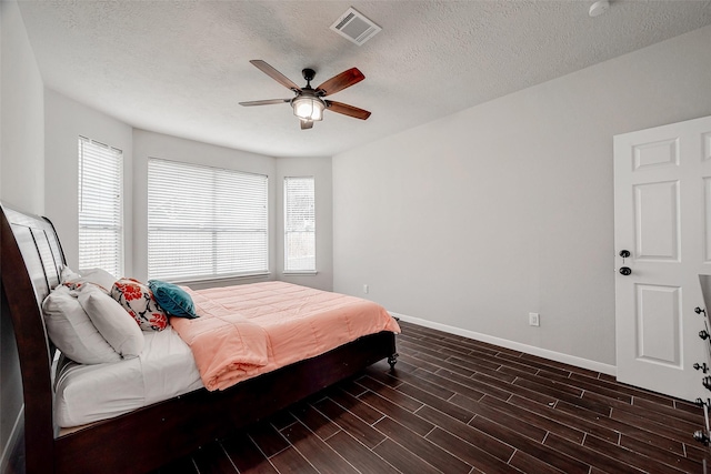 bedroom featuring a textured ceiling, ceiling fan, and dark wood-type flooring