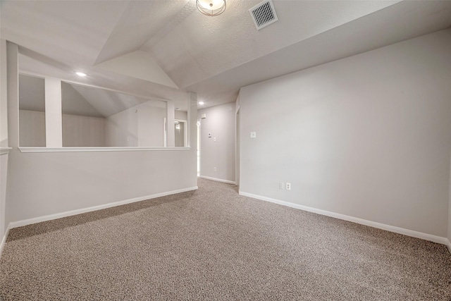 interior space with a textured ceiling, carpet floors, and vaulted ceiling