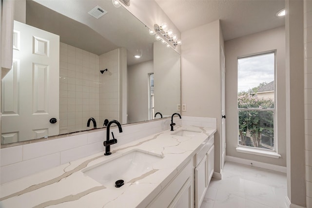 bathroom with a tile shower, vanity, a healthy amount of sunlight, and a textured ceiling