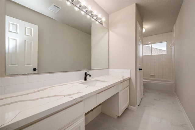 full bathroom featuring vanity, tiled shower / bath combo, a textured ceiling, and toilet