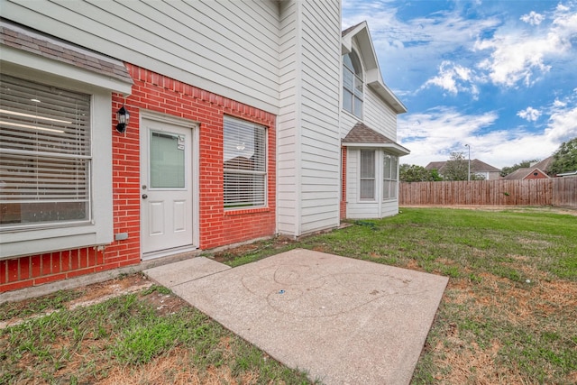 view of exterior entry featuring a patio area and a yard