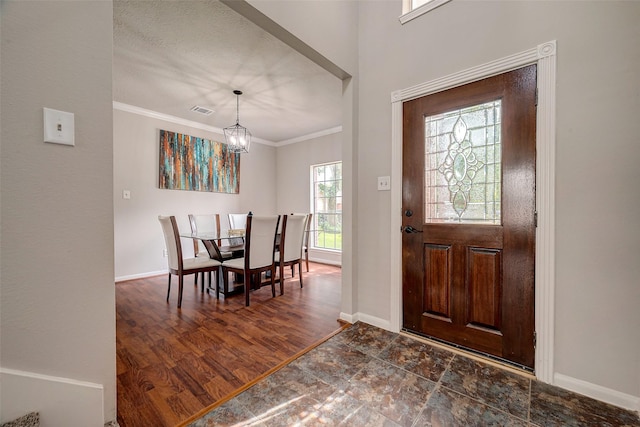 entryway featuring a textured ceiling, crown molding, dark hardwood / wood-style floors, and an inviting chandelier