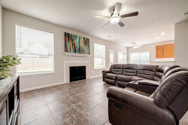 living room featuring dark tile patterned flooring, ceiling fan, and a textured ceiling