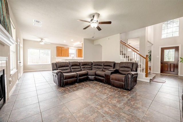 living room with ceiling fan, dark tile patterned flooring, and a textured ceiling